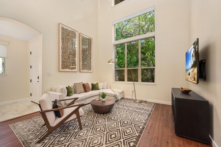 Unwind in your stylish living room with soaring ceilings and large windows that frame lush garden views.