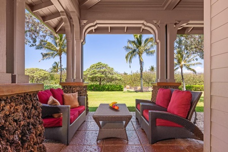 - Relax on this inviting covered lanai with plush red seating and a serene view - Tropical landscaping and palm trees create a peaceful island atmosphere - Perfect shaded spot to enjoy morning coffee or sunset conversations