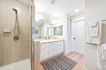 Ensuite primary bathroom with double vanity, walk-in shower, and tub