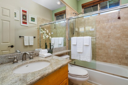 - Bathroom with granite vanity, glass enclosed shower, and tub combo - Neutral tiles and large mirror enhance the bright, clean atmosphere - Fresh towels and modern fixtures complete the functional design
