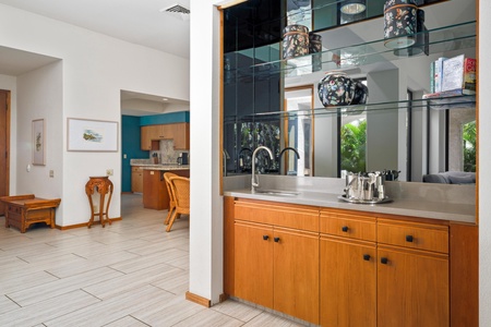 - Sleek wet bar with mirrored backsplash, dual sinks, and elegant lighting makes entertaining a breeze - Conveniently located off the kitchen and dining area for easy hosting - Store glassware, mix drinks, or enjoy morning coffee in this versatile nook