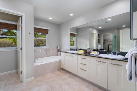 - Spacious bathroom with double vanity, oversized mirror, and relaxing soaking tub - Natural light flows in through the window above the tile accented tub corner - Fully stocked counters with towels and toiletries make you feel right at home