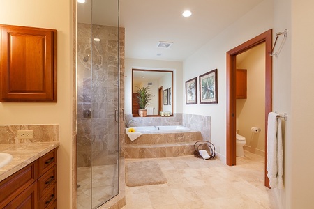 - Spacious bathroom with a marble tiled soaking tub and walk in glass shower   - Neutral tones and framed art add a warm, refined touch to the bright space   - Open design leads to a private toilet area for added convenience and privacy
