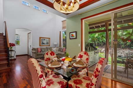 - Dining area with floral and striped upholstered chairs around a glass table - Large sliding doors open to the outdoor grill and beautiful greenery - Tray ceiling and chandelier add elegance to this inviting space