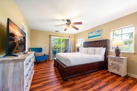 Sink into crisp linens and let the gentle ceiling fan lull you to sleep in your peaceful bedroom retreat, where warm wood floors and breezy balcony access create a relaxing coastal vibe.
