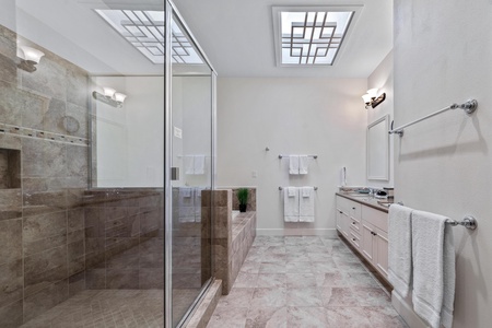 Ensuite primary bathroom with double vanity, walk-in shower, and soaking tub