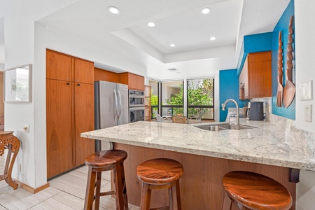 - Modern kitchen island with granite countertops and sleek wood bar stools creates a casual hangout spot - Prep meals, serve drinks, or chat with friends while enjoying views of the garden - Recessed lights and clean design make cooking a joy