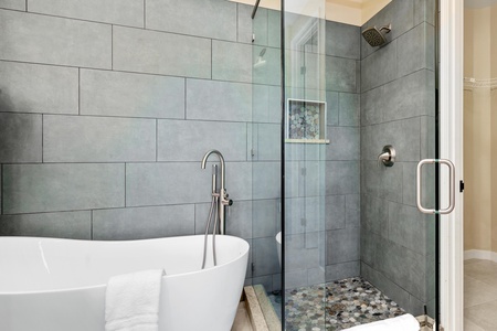 Remodeled primary bathroom with double vanity, walk-in shower, and soaking tub