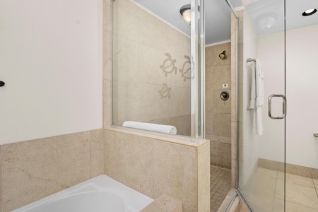 Relax in your elegant marble bathroom featuring a deep soaking tub and spacious glass shower for the ultimate unwind experience.