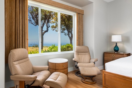 - Pair of cushioned recliners positioned by a window with serene ocean and tree views - Round wood side table offers a handy spot for drinks or books while relaxing - Natural light and peaceful scenery make this corner ideal for unwinding