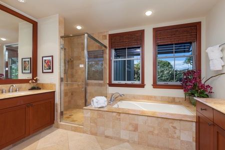 - Elegant bathroom with glass enclosed shower and soaking tub surrounded by warm stone tiles - Large windows provide natural light and views for a serene atmosphere - Spacious design blends comfort and style for a relaxing retreat