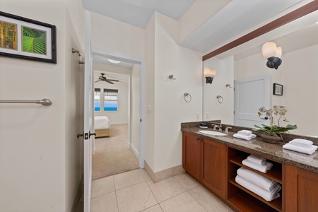 Your spacious bathroom features granite counters, rich wood cabinetry, and fluffy towels, with glimpses of your bedroom beyond.