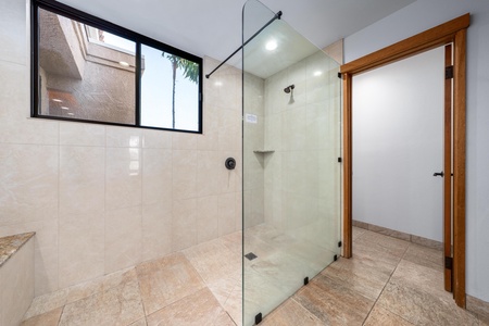 Step into your spacious glass-enclosed shower with natural light streaming through the window, creating a bright and airy bathing experience.