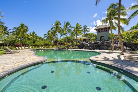 Tropical paradise pool surrounded by swaying palms and lush gardens under brilliant blue skies.