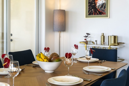 - Dining table set with elegant dishware and fresh tropical fruit display   - Deep blue chairs contrast beautifully with the warm wood tabletop   - Perfect for enjoying meals together in a stylish inviting setting