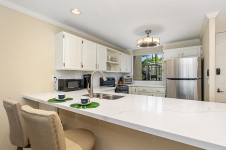 - Sleek breakfast bar offers space for morning coffee or evening cocktails - Clean modern kitchen features updated appliances and a bright tropical vibe - Thoughtful touches like leaf placemats and warm lighting add island charm