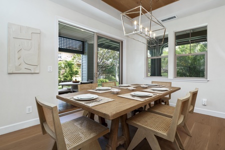 Gather around your elegant dining table where warm wood meets modern style, perfect for sharing memorable meals with tropical garden views.