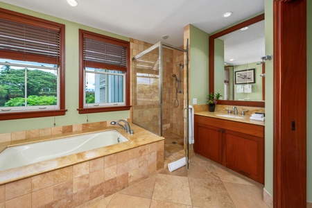 Your private sanctuary features a luxurious soaking tub and walk-in shower, framed by natural light and lush green views just beyond your windows.