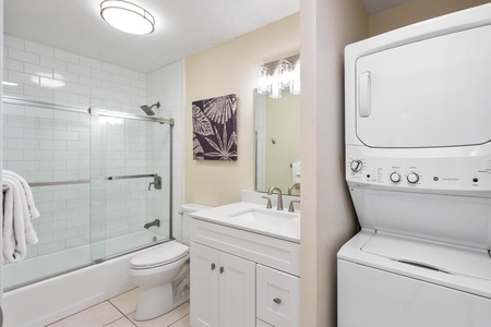 - Modern bathroom with stacked washer and dryer makes long stays convenient - White vanity and walk in shower behind glass deliver a clean polished look - Compact and functional space perfect for freshening up and doing laundry