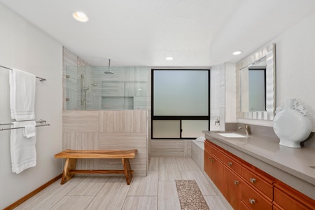 - Spacious bathroom with walk in shower, large frosted window, and a calming bench nook - Dual vanities and wood cabinetry offer convenience and storage - Clean lines and natural tones create a peaceful, spa style atmosphere