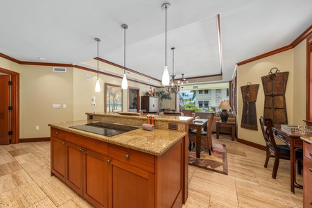 Inviting open-concept space with rich wood accents, warm tones, and spacious kitchen island with granite counters. Flows seamlessly into dining and living areas with tropical views.
