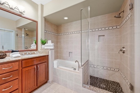 Ensuite primary bathroom with double vanity, walk-in shower, and soaking tub