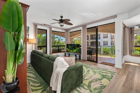 Unwind in your bright living space where tropical breezes flow through open doors and a cozy sofa invites relaxation beneath the gentle ceiling fan.