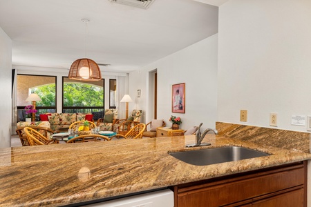 Your open kitchen flows beautifully into the living space, where tropical breezes drift through wide windows and wicker furniture invites relaxation.
