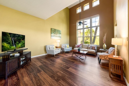 Relax in this bright, airy living room where soaring ceilings and sunlight through tall windows create a welcoming retreat for your Hawaiian getaway.