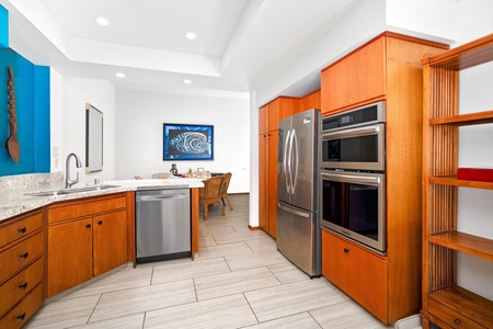 - Gourmet kitchen features double ovens, stainless steel fridge, and sleek cabinetry - Tile floors and crisp finishes offer a clean and polished cooking space - Open layout flows naturally into the dining area beyond