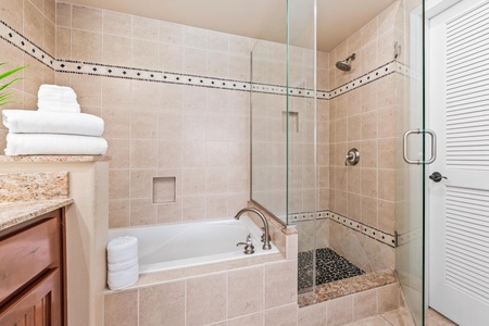 Ensuite primary bathroom with double vanity, walk-in shower, and soaking tub