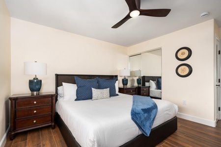 Sink into crisp white linens with navy accents in your serene bedroom. The elegant ceiling fan keeps you cool while mirrored closets add space and light.