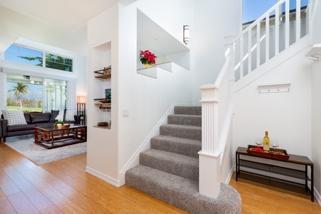 - Bright stairwell leads upstairs with soft carpet steps and modern white railing - Built in shelving and greenery add charm to the open airy design - Warm wood floors and stylish accents set a welcoming tone throughout