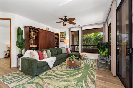Sink into the plush green sofa and unwind in your sunlit living room, where tropical garden views and thoughtfully curated furnishings create your perfect relaxation haven.