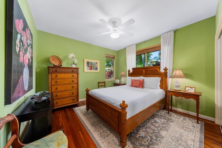 - Cozy bedroom with wooden bed frame, dresser, and vibrant green walls - Large windows with white curtains bring in natural light and views - Warm wood floors and classic decor create a welcoming retreat