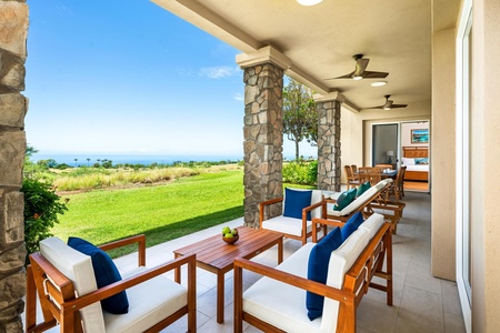 - Spacious covered patio with stylish wood seating and deep blue accent pillows - Overlooks a wide expanse of green lawn leading to panoramic ocean views - Ideal for outdoor gatherings, shaded relaxation, and breezy coastal living