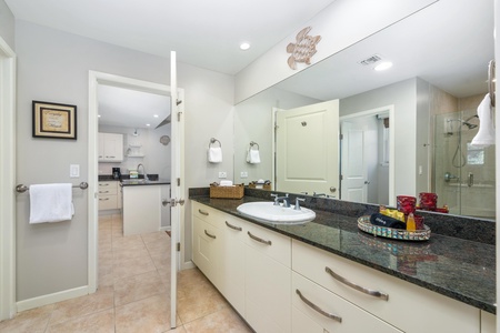 - Full guest bath includes a granite counter, wide mirror, and fresh white towels - Located just off the hallway with easy access from the living and bedroom areas - Thoughtfully stocked with bath essentials and bright neutral finishes
