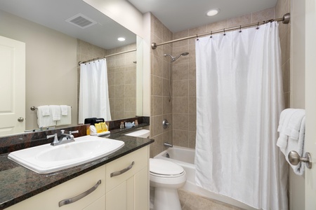 - Modern guest bath includes a full shower and tub combo with tiled surround - Vanity with granite countertop and mirror offers space for your essentials - Soft lighting and stocked amenities ensure a relaxing experience