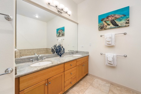 Fresh towels await in your spacious bathroom, where ocean-themed art and dual vanities create a serene coastal retreat.