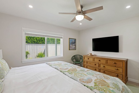 Your serene bedroom features a comfortable bed, ceiling fan, entertainment center, and peaceful garden views for restful nights.