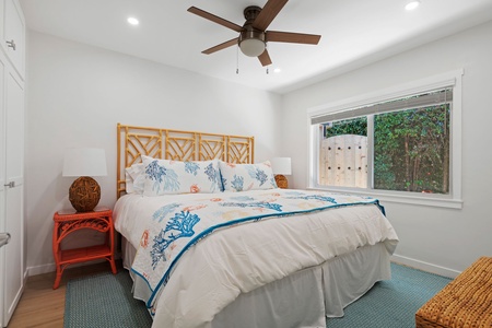 Your bright bedroom features a bamboo headboard, ceiling fan, and garden views for peaceful rest after beach adventures.