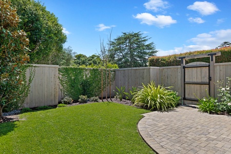 Step into your private backyard oasis, where manicured lawn meets charming paved paths—perfect for morning coffee or evening relaxation.