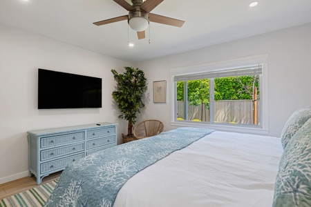 Rest easy in your serene bedroom with crisp linens, ceiling fan, entertainment center, and peaceful garden views.