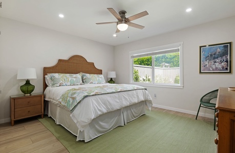 Unwind in your serene bedroom with coastal charm, featuring a woven headboard, soft linens, and garden views through bright windows.