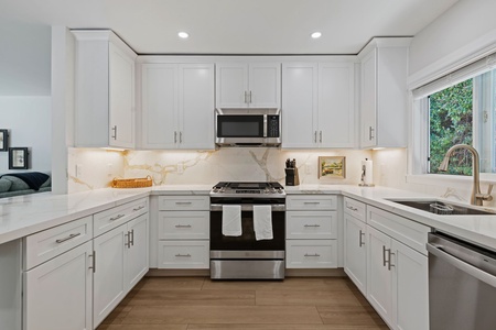 You'll love cooking in this bright, modern kitchen with gleaming white cabinets, elegant countertops, and high-end stainless steel appliances.