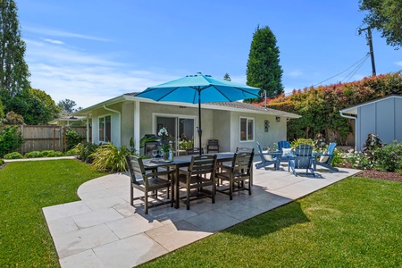 Step onto your private patio where outdoor dining awaits under a bright umbrella, surrounded by lush landscaping and endless blue skies.