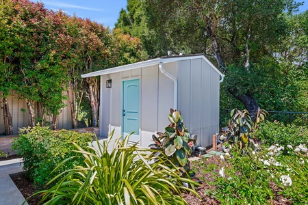Modern guest unit nestled in lush landscaping with tropical plants and mature trees creating a private garden retreat.