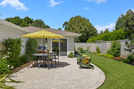 Beautiful landscaped backyard with paved patio, outdoor dining, and mature trees creating a peaceful retreat.