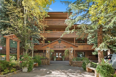 A multi-story wooden building with balconies surrounded by trees, with a sign indicating "Fasching Haus" and parking information at the entrance.