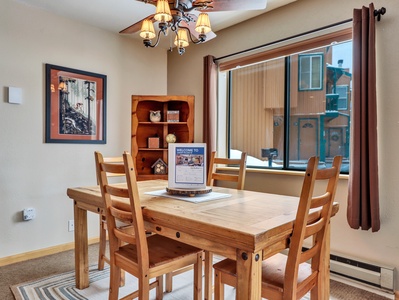 Bright and welcoming dining area with seating for four, a ceiling fan for added comfort, and a convenient cupboard for extra storage